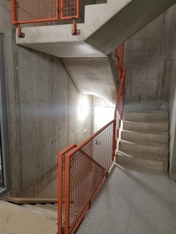 Treppenhaus Kienitzer 3 mit Sichtbeton und rotem Geländer